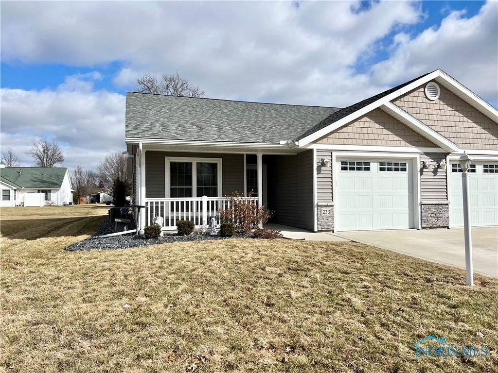 view of front of home with a porch, an attached garage, a shingled roof, driveway, and a front yard