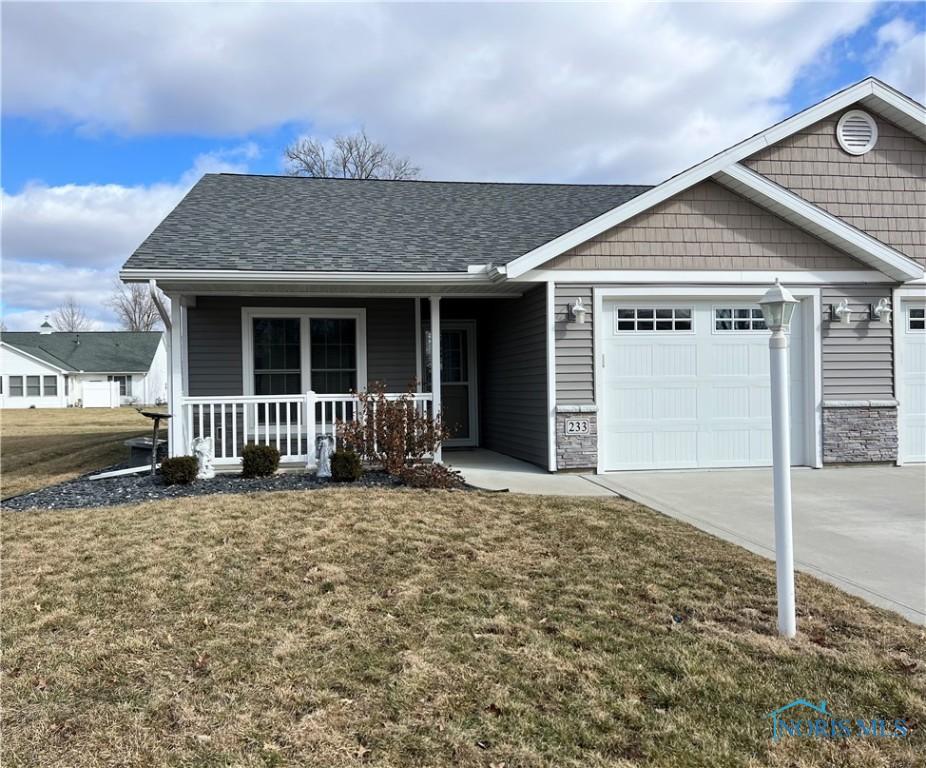 view of front of property with roof with shingles, covered porch, a garage, driveway, and a front lawn