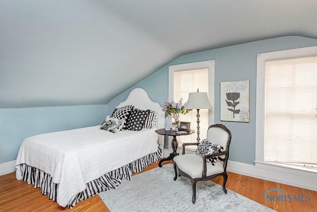 bedroom with lofted ceiling, baseboards, and wood finished floors