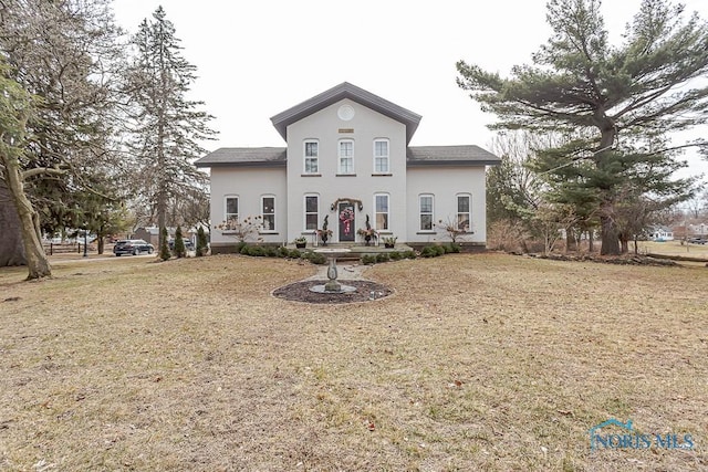 view of front of house with a front lawn, a shingled roof, and stucco siding