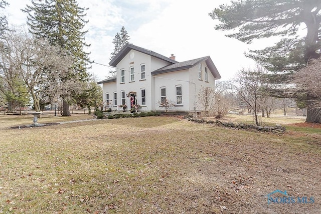 view of front of property with a front yard, a chimney, and stucco siding