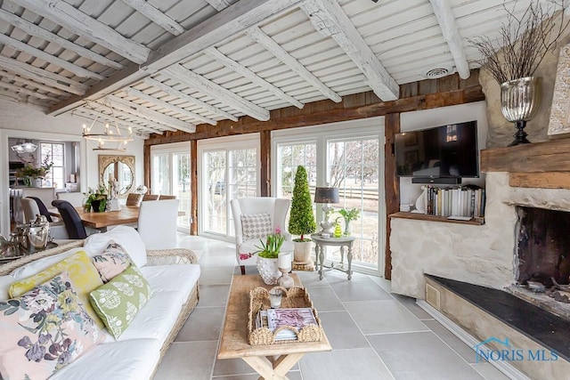 living area with a fireplace, plenty of natural light, tile patterned flooring, and visible vents