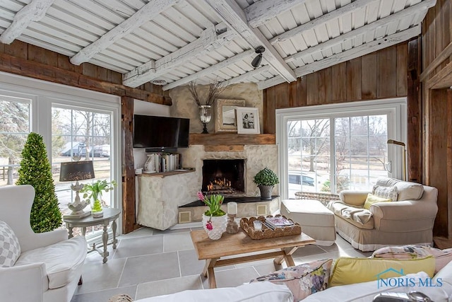 living area featuring wood walls, plenty of natural light, a fireplace, and tile patterned flooring