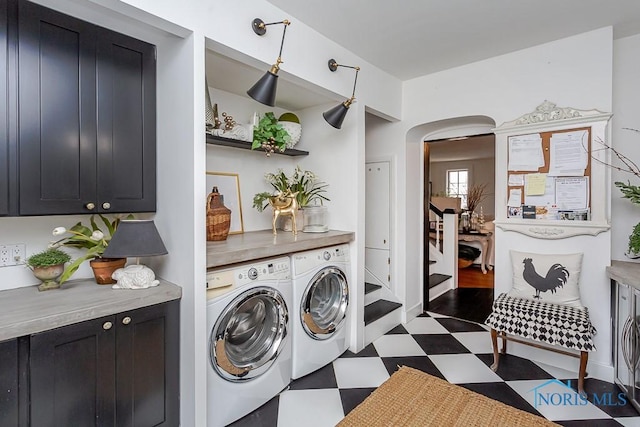 laundry area featuring arched walkways, independent washer and dryer, cabinet space, and tile patterned floors