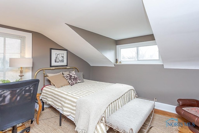 bedroom with vaulted ceiling, baseboards, and wood finished floors