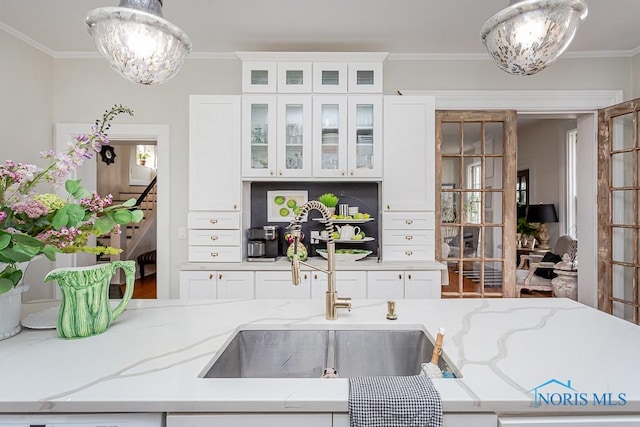 kitchen featuring decorative backsplash, hanging light fixtures, an inviting chandelier, crown molding, and a sink