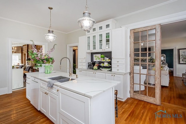 kitchen with decorative light fixtures, ornamental molding, white dishwasher, a sink, and wood finished floors