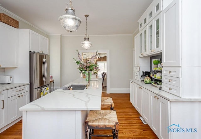 kitchen featuring freestanding refrigerator, a center island, a kitchen bar, and wood finished floors