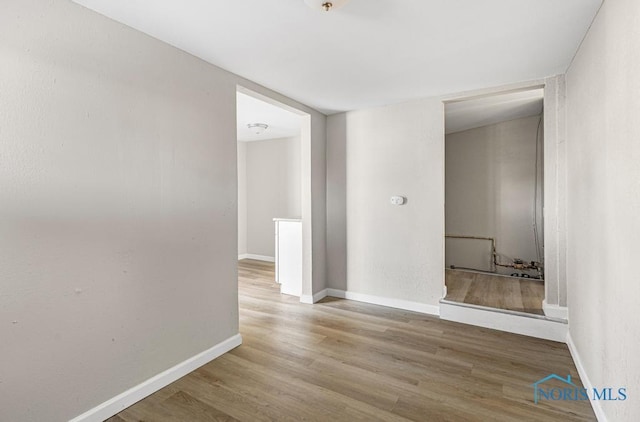 spare room with baseboards and wood finished floors