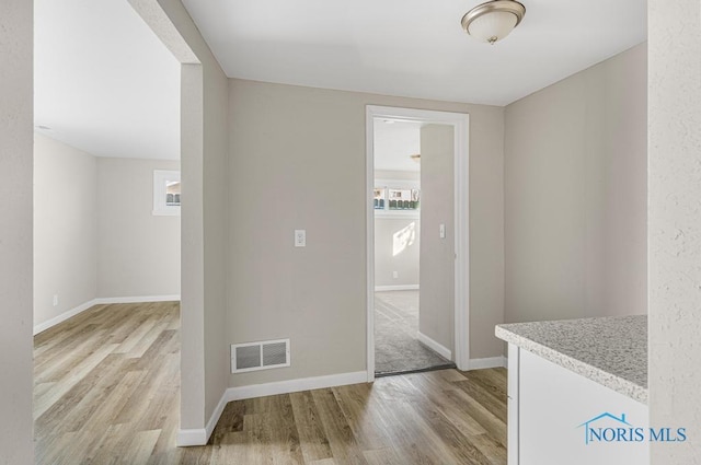 interior space with light wood-type flooring, visible vents, and baseboards