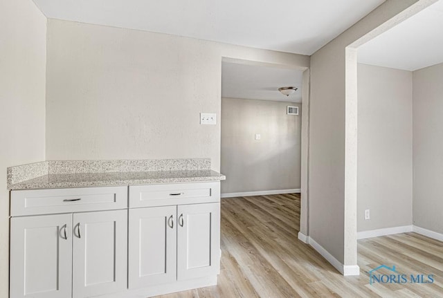 5728 Rudyard Rd, Sylvania, OH 43560 - interior space with baseboards, light stone countertops, white cabinets, and light wood-type flooring