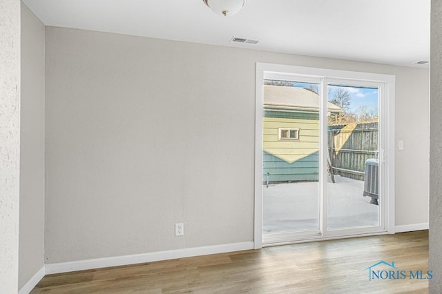 doorway featuring visible vents, baseboards, and wood finished floors