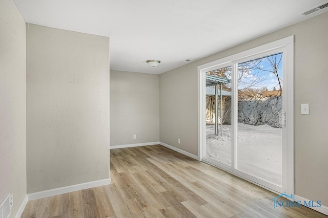 unfurnished room with light wood finished floors, baseboards, and visible vents