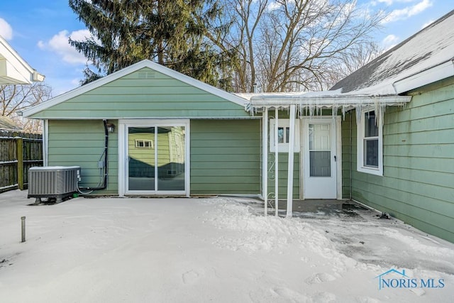 snow covered house with fence and cooling unit