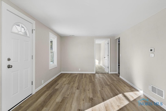 foyer featuring baseboards, visible vents, and wood finished floors