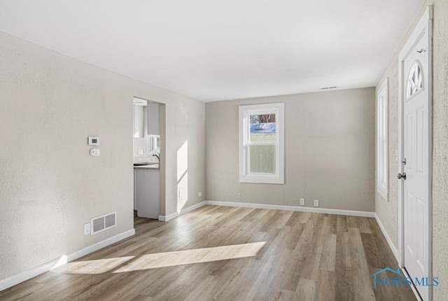 interior space with wood finished floors, visible vents, and baseboards