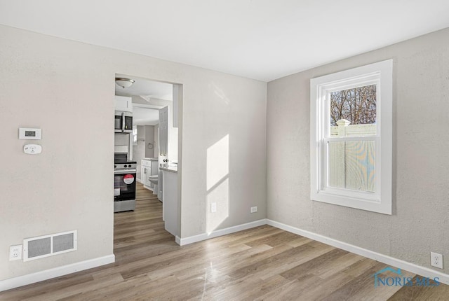 empty room featuring baseboards, visible vents, and light wood-style floors