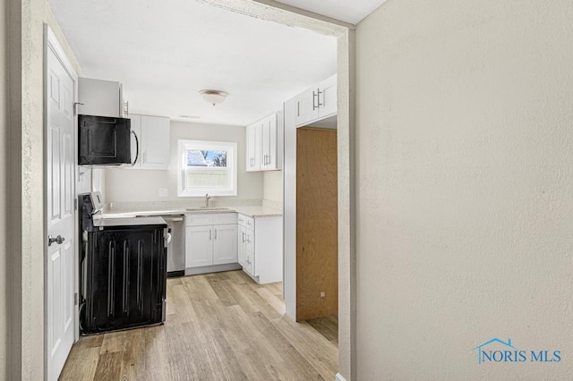 kitchen with electric stove, light wood finished floors, light countertops, white cabinetry, and a sink