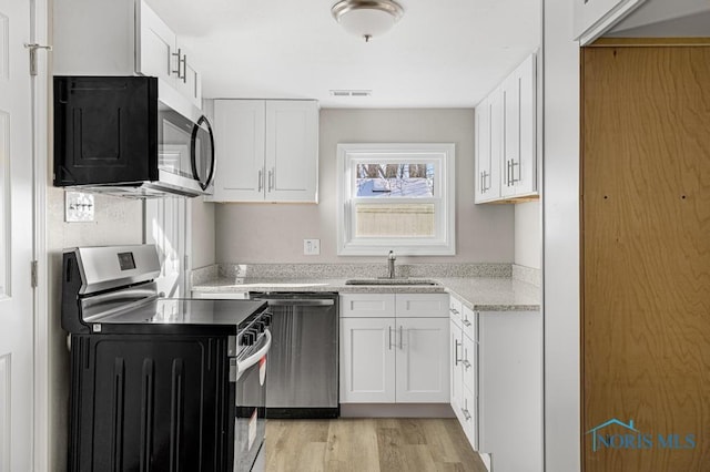 kitchen featuring appliances with stainless steel finishes, visible vents, a sink, and white cabinetry