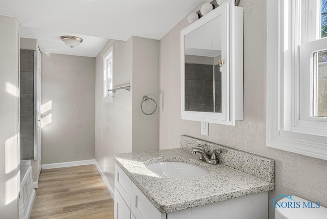 bathroom with toilet, baseboards, wood finished floors, and vanity