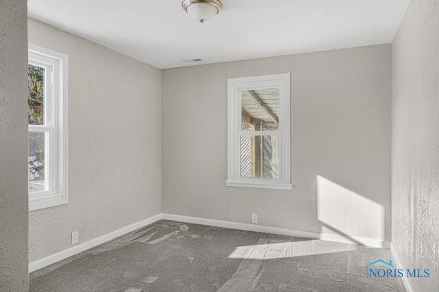 carpeted spare room featuring baseboards and visible vents