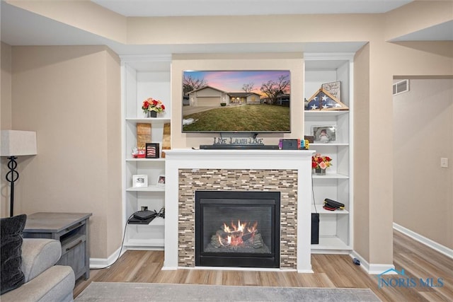 living area with baseboards, visible vents, wood finished floors, and a tile fireplace