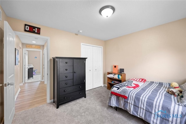 bedroom featuring light carpet, baseboards, and a closet