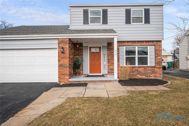 view of front facade featuring an attached garage, roof with shingles, a front lawn, and brick siding