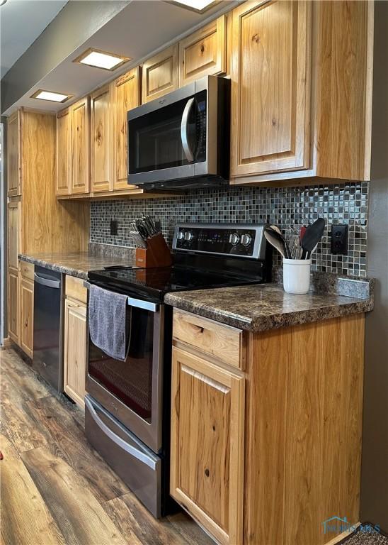 kitchen featuring stainless steel appliances, dark wood-style flooring, and tasteful backsplash