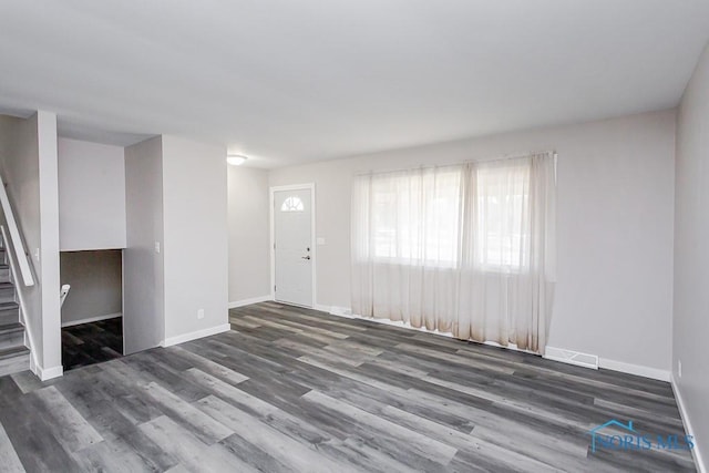 unfurnished living room with stairway, wood finished floors, visible vents, and baseboards