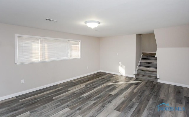 empty room with wood finished floors, visible vents, baseboards, and stairs