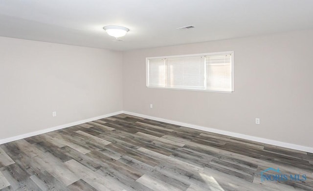 spare room featuring baseboards, visible vents, and wood finished floors