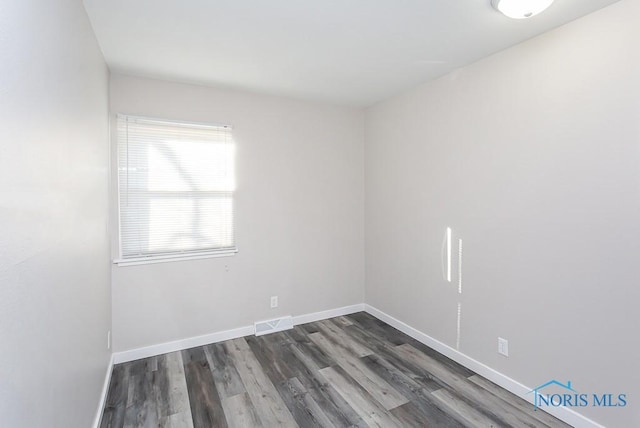 empty room featuring baseboards, visible vents, and dark wood-type flooring