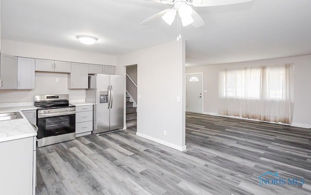 kitchen featuring stainless steel appliances, light countertops, gray cabinetry, light wood-style floors, and baseboards