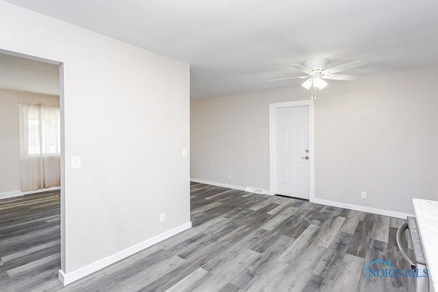 unfurnished room featuring wood finished floors, a ceiling fan, and baseboards