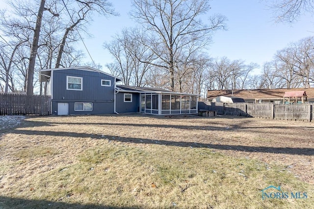 rear view of house with fence private yard, a sunroom, and a yard