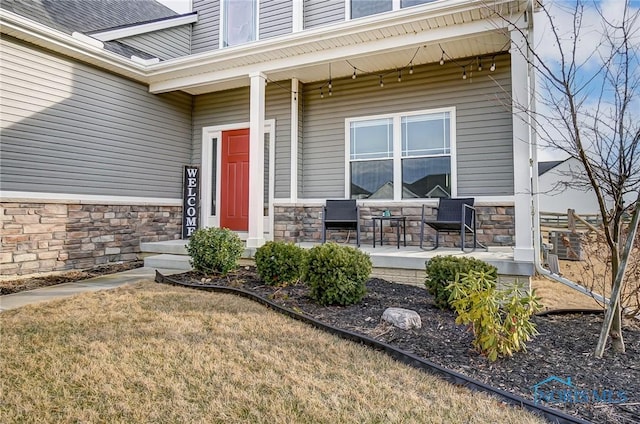 view of exterior entry with stone siding and covered porch