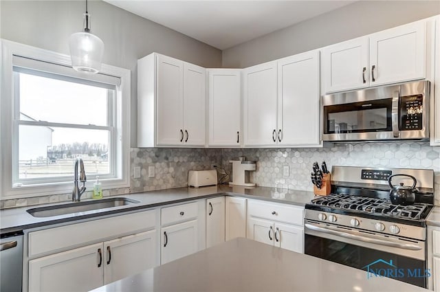 kitchen featuring appliances with stainless steel finishes, backsplash, a sink, and white cabinetry