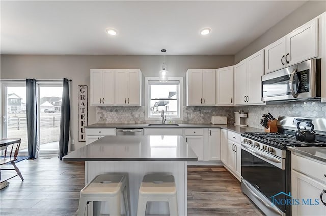 kitchen featuring stainless steel appliances, a breakfast bar, a sink, white cabinets, and decorative backsplash