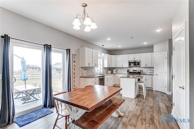 dining space with light wood-type flooring, a chandelier, and recessed lighting