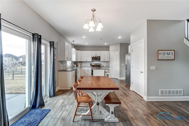 dining space featuring light wood-style flooring, visible vents, and baseboards