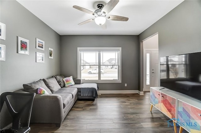 living area with dark wood-style floors, baseboards, and a ceiling fan