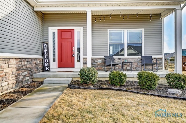 view of exterior entry featuring covered porch and stone siding