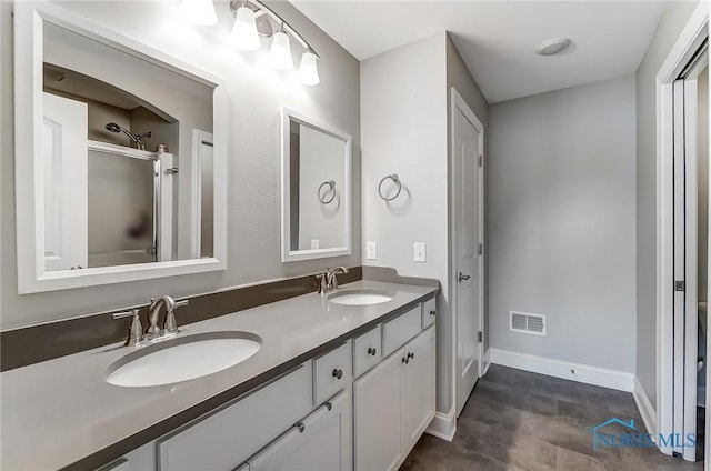 full bath featuring visible vents, a sink, a shower with door, and double vanity