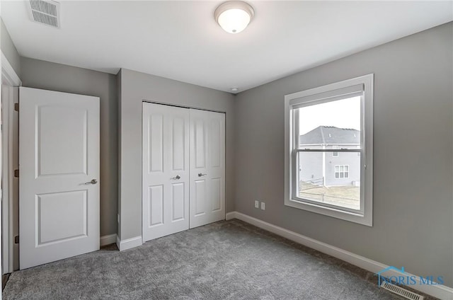 unfurnished bedroom featuring carpet floors, baseboards, visible vents, and a closet