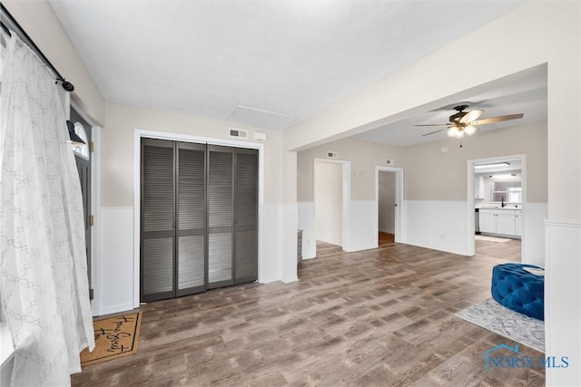 unfurnished bedroom with ensuite bath, a closet, wainscoting, and wood finished floors