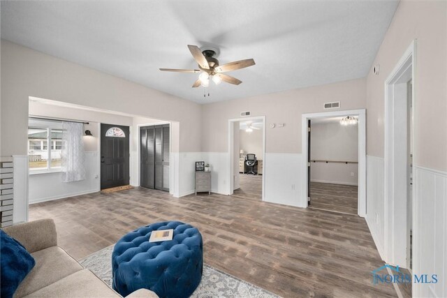 sitting room featuring a wainscoted wall, ceiling fan, wood finished floors, and visible vents