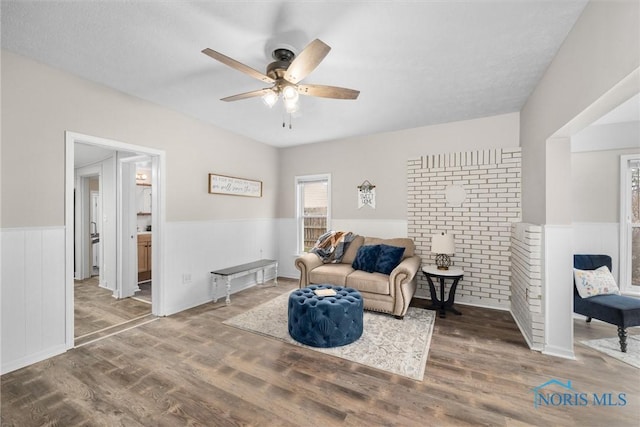 sitting room featuring a wainscoted wall, ceiling fan, and wood finished floors