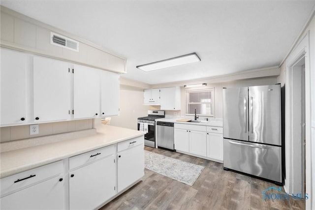 kitchen featuring stainless steel appliances, a sink, visible vents, and white cabinetry