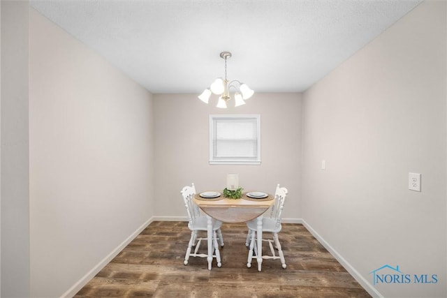 unfurnished dining area featuring a notable chandelier, baseboards, and wood finished floors